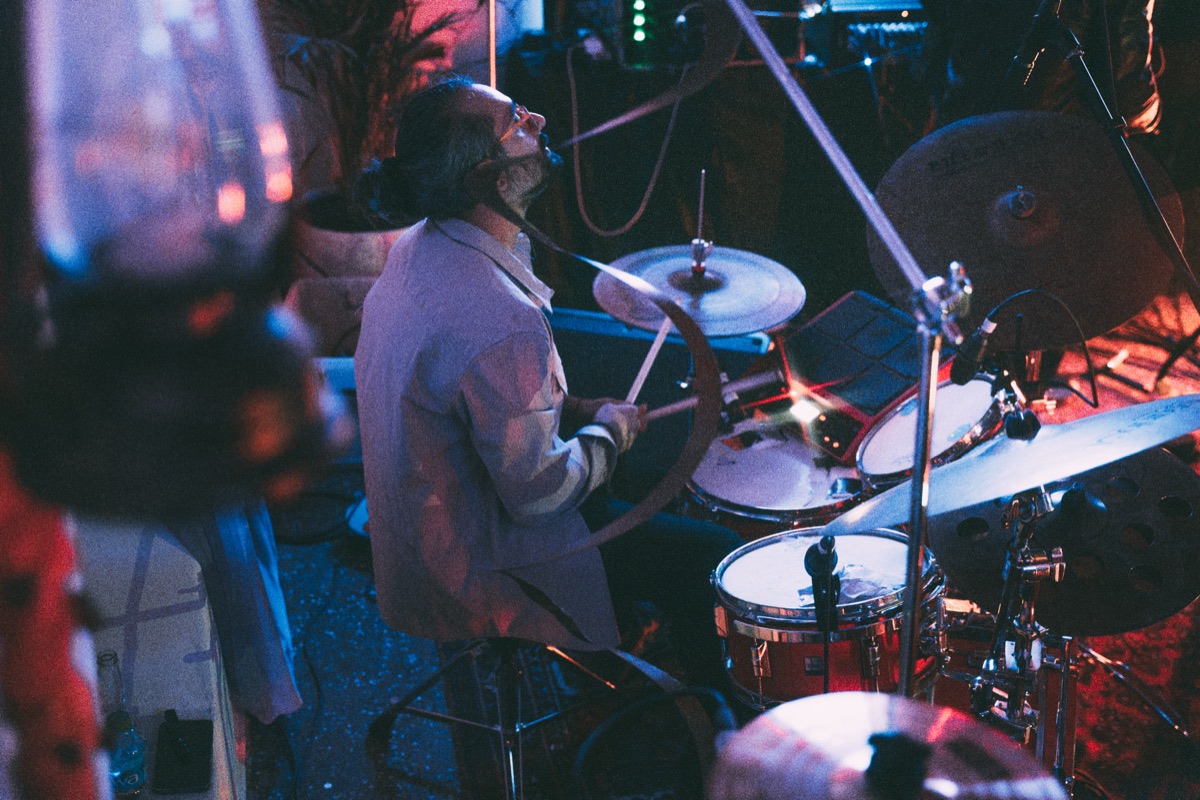 The drummer mid-fill under red and blue light