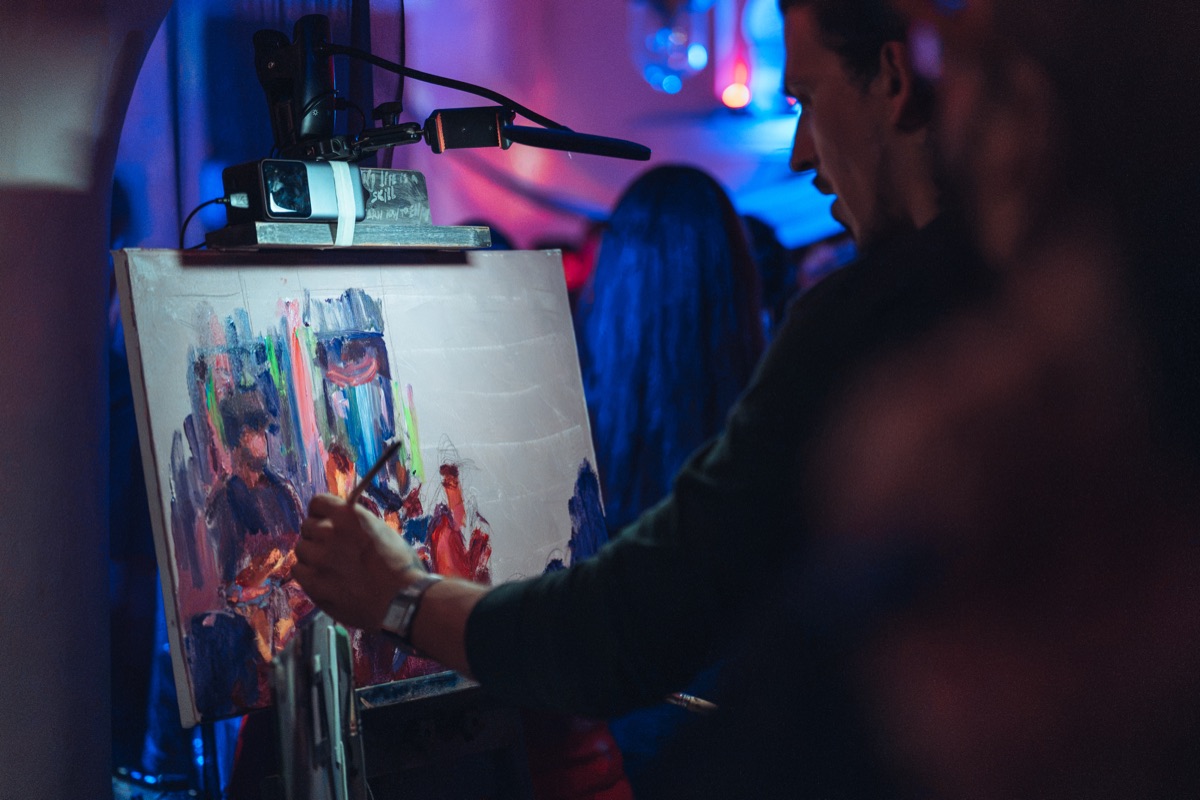 A painter working at an easel beside the stage