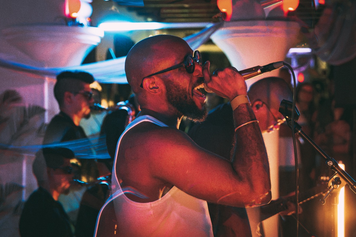 The singer in a white vest, horns behind