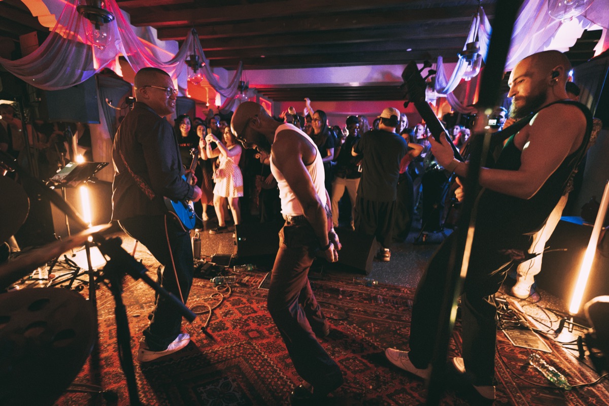 The band dancing on stage, the room behind them